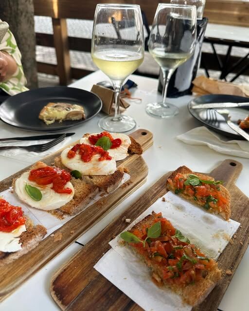 Bruschettas em tábuas de madeira e dois copos de vinho branco numa mesa da esplanada