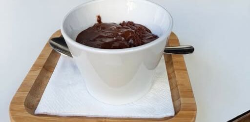Mousse de chocolate numa taça branca sobre tabuleiro de madeira